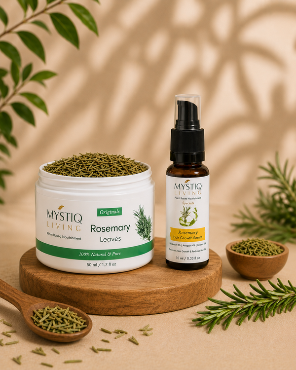 Mystiq Living Rosemary Leaves hair growth treatment shown as a white jar filled with dried green leaves next to a small amber spray bottle, styled on a wooden block with rosemary sprigs and a spoonful of the leaves.